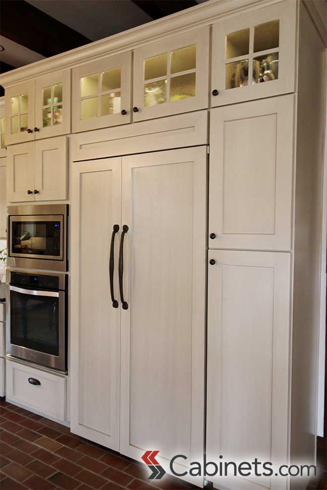 Lantlig inredning av ett stort kök, med en rustik diskho, skåp i shakerstil, vita skåp, vitt stänkskydd, rostfria vitvaror, tegelgolv och en köksö