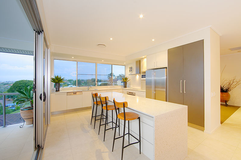 Example of a trendy kitchen design in Brisbane with white cabinets, granite countertops, stainless steel appliances and an island