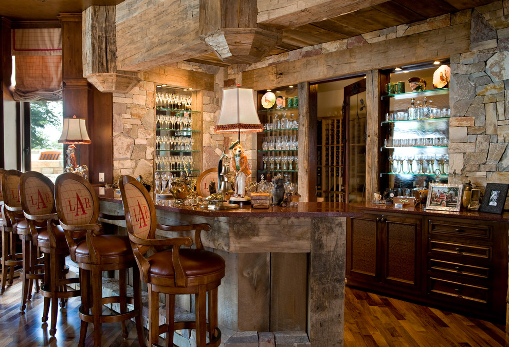 Example of a tuscan medium tone wood floor home bar design in Minneapolis with recessed-panel cabinets, dark wood cabinets, granite countertops and stone slab backsplash