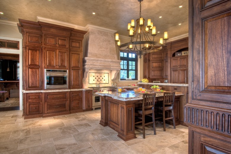 This is an example of a traditional u-shaped kitchen/diner in Salt Lake City with beaded cabinets, medium wood cabinets, granite worktops, beige splashback, stainless steel appliances, travertine flooring, an island and stone tiled splashback.