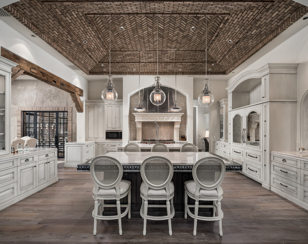 Inspiration for a huge mediterranean u-shaped dark wood floor, brown floor and tray ceiling open concept kitchen remodel in Phoenix with raised-panel cabinets, light wood cabinets, quartzite countertops, multicolored backsplash, two islands, multicolored countertops, a drop-in sink and mosaic tile backsplash