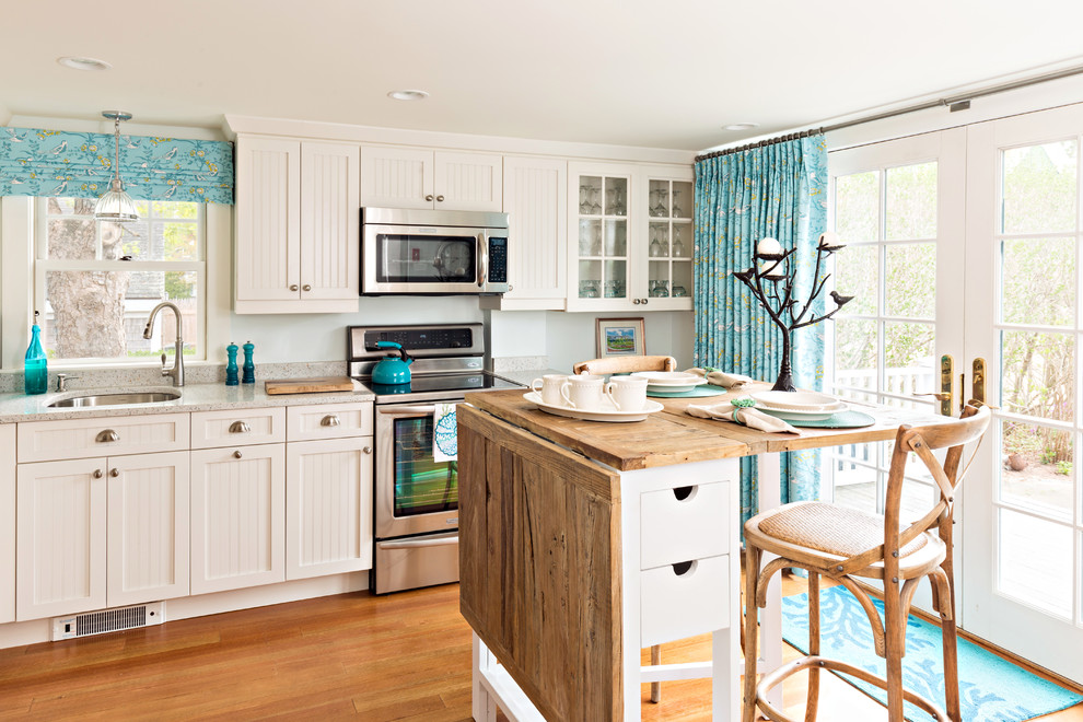 This is an example of a coastal kitchen in Boston with a submerged sink, shaker cabinets, white cabinets, stainless steel appliances, medium hardwood flooring, an island, brown floors and grey worktops.