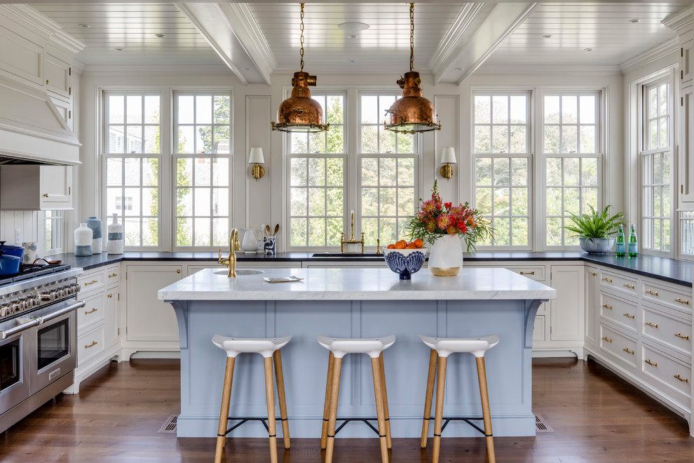 Maritime Küche in U-Form mit Schrankfronten mit vertiefter Füllung, weißen Schränken, Rückwand-Fenster, Küchengeräten aus Edelstahl, braunem Holzboden und Kücheninsel in Boston