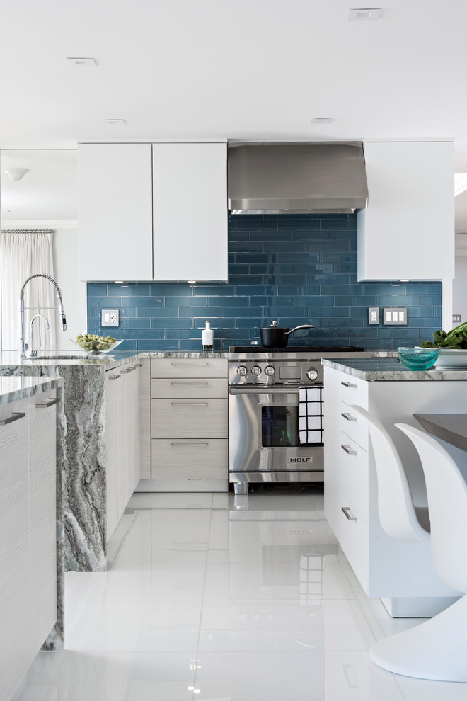 Large trendy u-shaped ceramic tile and white floor open concept kitchen photo in Boston with an undermount sink, flat-panel cabinets, white cabinets, granite countertops, blue backsplash, subway tile backsplash, stainless steel appliances, an island and multicolored countertops