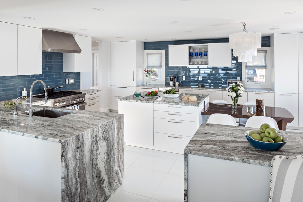 Inspiration for a large contemporary u-shaped open plan kitchen in Boston with a submerged sink, flat-panel cabinets, white cabinets, granite worktops, blue splashback, metro tiled splashback, stainless steel appliances, ceramic flooring, an island, white floors and multicoloured worktops.
