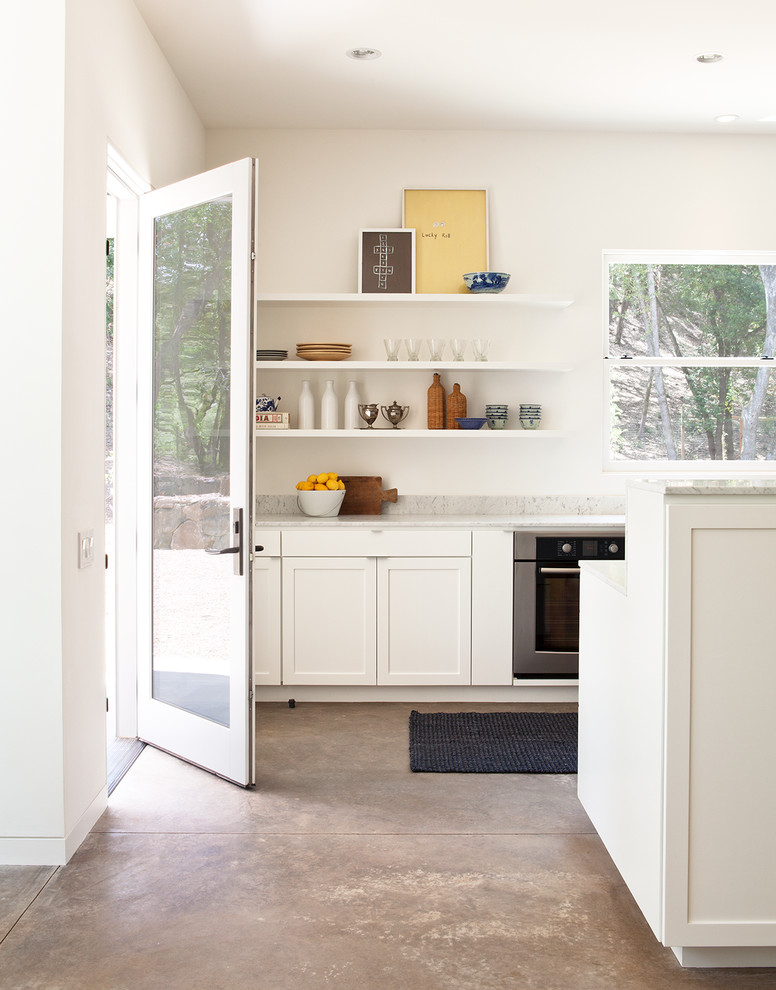 Bild på ett mellanstort funkis grå grått kök, med skåp i shakerstil, vita skåp, betonggolv, marmorbänkskiva, rostfria vitvaror, en köksö och grått golv