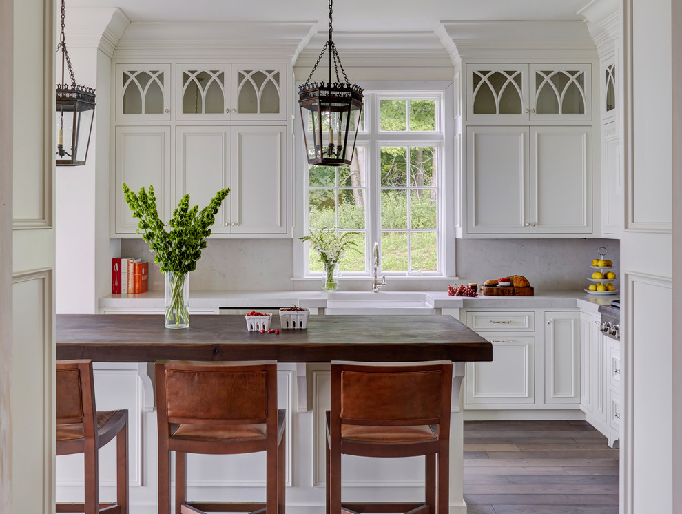 Idéer för att renovera ett avskilt vintage grå grått kök, med en rustik diskho, luckor med infälld panel, vita skåp, grått stänkskydd, stänkskydd i sten, mörkt trägolv, en köksö, brunt golv, bänkskiva i kvarts och rostfria vitvaror