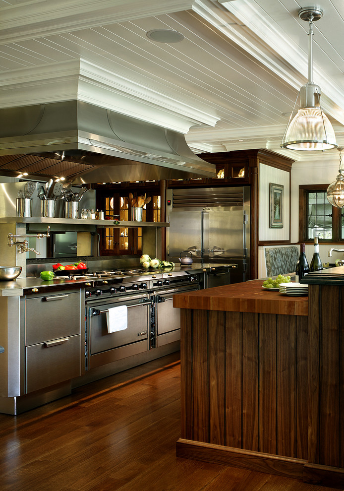 Example of a large transitional dark wood floor eat-in kitchen design in New York with flat-panel cabinets, stainless steel cabinets, wood countertops and stainless steel appliances