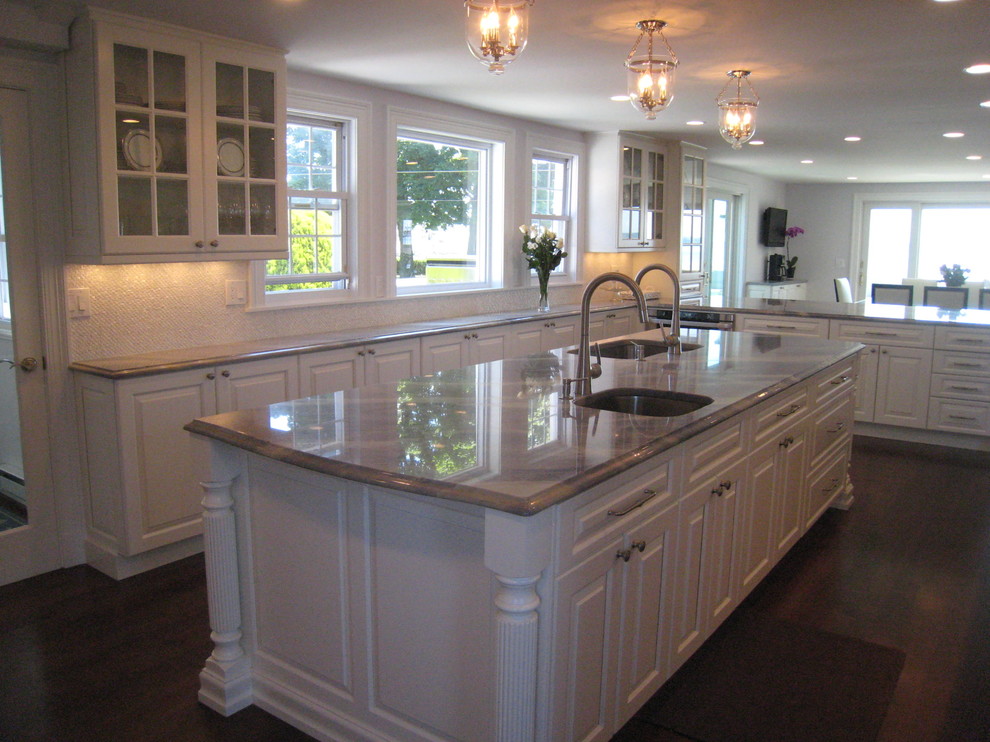 Large classic l-shaped enclosed kitchen in New York with raised-panel cabinets, white cabinets, granite worktops, white splashback, dark hardwood flooring and an island.