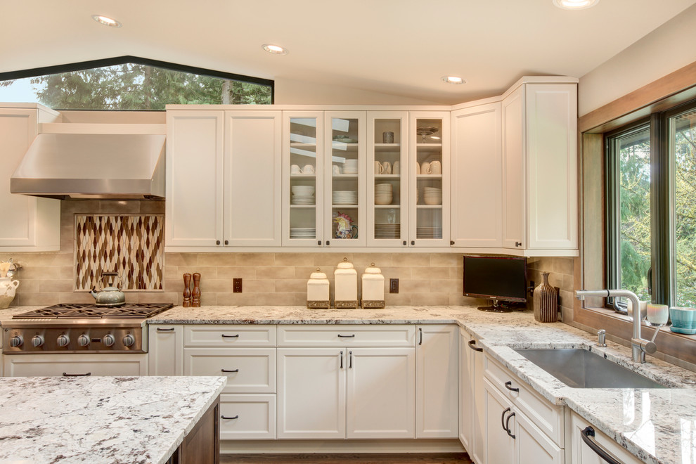 Klassische Küche mit weißen Schränken, Granit-Arbeitsplatte, bunter Rückwand, Rückwand aus Keramikfliesen, Küchengeräten aus Edelstahl und braunem Holzboden in Seattle