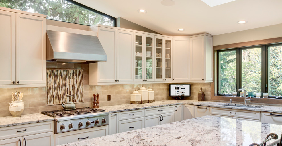 Klassisk inredning av ett kök, med vita skåp, granitbänkskiva, flerfärgad stänkskydd, stänkskydd i keramik, rostfria vitvaror och mellanmörkt trägolv