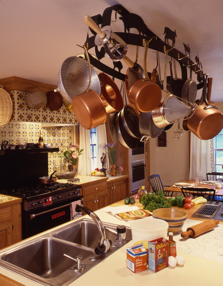 Esempio di una cucina chic con lavello a doppia vasca, ante con bugna sagomata, ante marroni, top in granito, paraspruzzi arancione, paraspruzzi con lastra di vetro e elettrodomestici neri