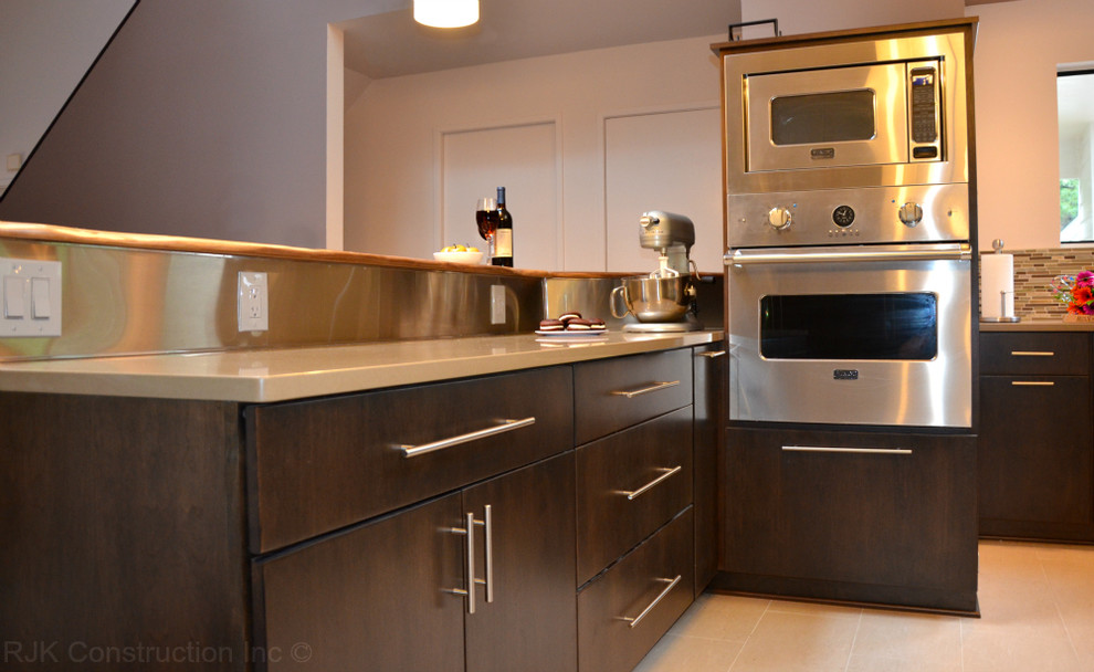 Foto på ett mellanstort funkis kök, med en undermonterad diskho, släta luckor, skåp i mörkt trä, bänkskiva i koppar, brunt stänkskydd, stänkskydd i metallkakel, rostfria vitvaror, klinkergolv i porslin och en köksö