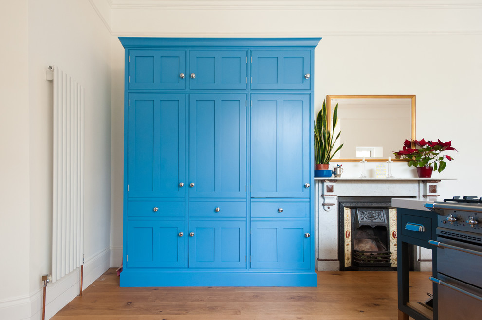 Diseño de cocina actual con puertas de armario azules y suelo de madera clara