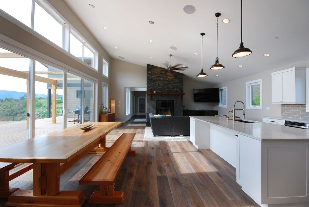 Example of a large transitional l-shaped medium tone wood floor and brown floor eat-in kitchen design in Seattle with an undermount sink, shaker cabinets, white cabinets, marble countertops, gray backsplash, subway tile backsplash, stainless steel appliances and an island