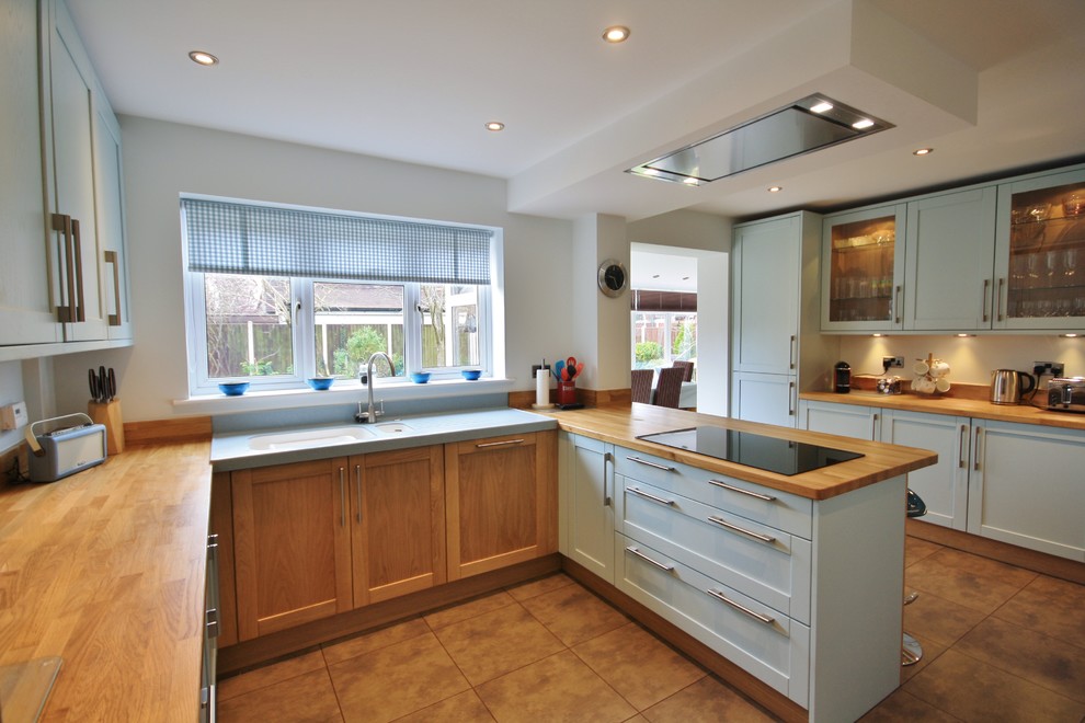 Foto di una grande cucina ad ambiente unico design con lavello integrato, ante in stile shaker, ante blu, top in legno e elettrodomestici neri