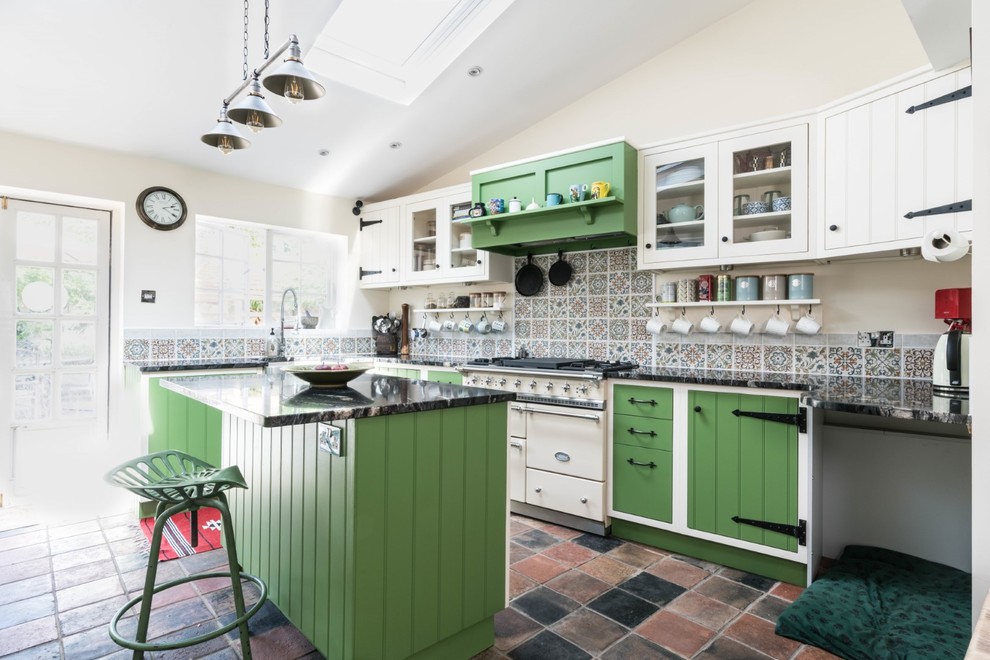 Small country l-shaped porcelain tile and multicolored floor eat-in kitchen photo in Essex with a farmhouse sink, green cabinets, granite countertops, multicolored backsplash, mosaic tile backsplash, paneled appliances, an island and black countertops