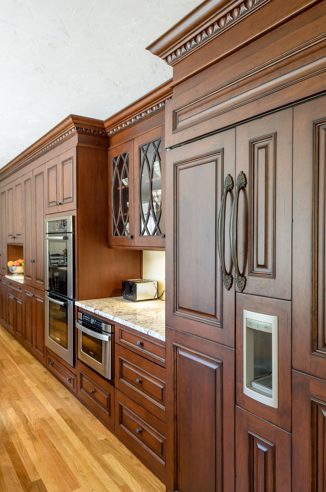 Inspiration for a timeless galley eat-in kitchen remodel in Boston with an undermount sink, raised-panel cabinets, brown cabinets, granite countertops and stainless steel appliances