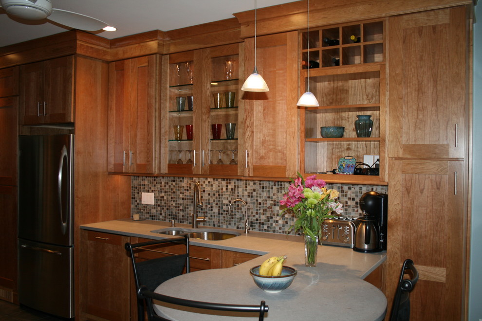 Foto på ett mellanstort vintage kök, med en undermonterad diskho, luckor med infälld panel, skåp i mellenmörkt trä, bänkskiva i kvarts, brunt stänkskydd, stänkskydd i mosaik, rostfria vitvaror, ljust trägolv och en halv köksö