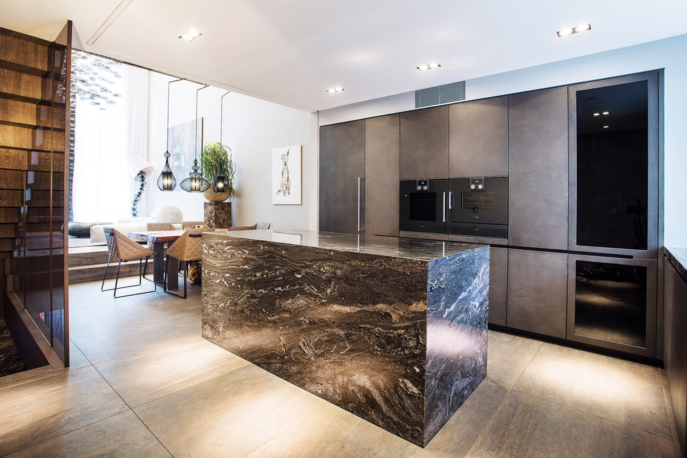Design ideas for a medium sized contemporary l-shaped kitchen/diner in London with flat-panel cabinets, grey cabinets, integrated appliances, an island, grey floors, marble worktops and black worktops.