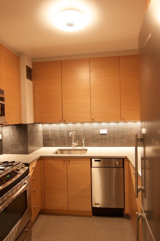 Photo of a small bohemian u-shaped enclosed kitchen in New York with a submerged sink, flat-panel cabinets, light wood cabinets, quartz worktops, grey splashback, glass tiled splashback, stainless steel appliances, porcelain flooring and no island.