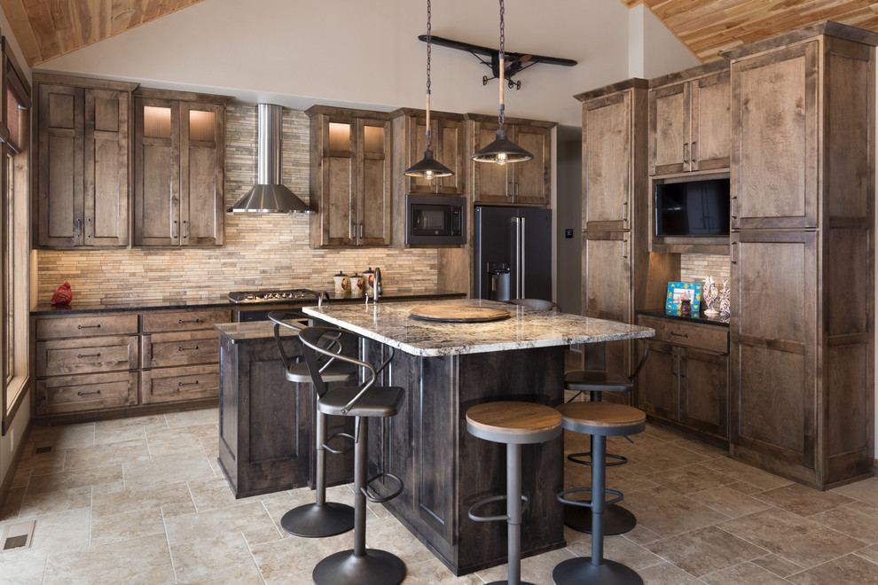 This is an example of a rustic l-shaped kitchen in Minneapolis with shaker cabinets, dark wood cabinets, beige splashback, matchstick tiled splashback, black appliances, an island, beige floors and black worktops.