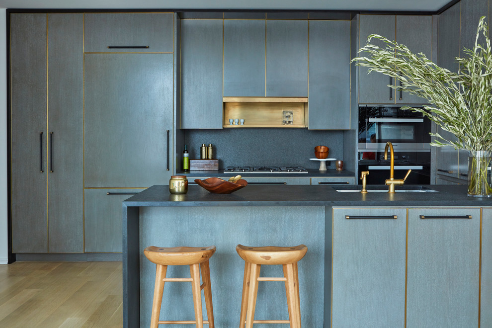 Пример оригинального дизайна: угловая кухня в современном стиле с врезной мойкой, плоскими фасадами, синими фасадами, техникой под мебельный фасад, светлым паркетным полом и полуостровом