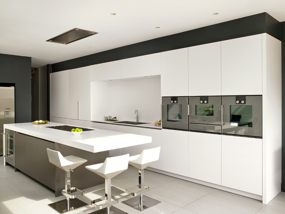 ロンドンにある広いコンテンポラリースタイルのおしゃれなキッチン (ダブルシンク、フラットパネル扉のキャビネット、白いキャビネット、白いキッチンパネル、シルバーの調理設備、セラミックタイルの床、ベージュの床) の写真