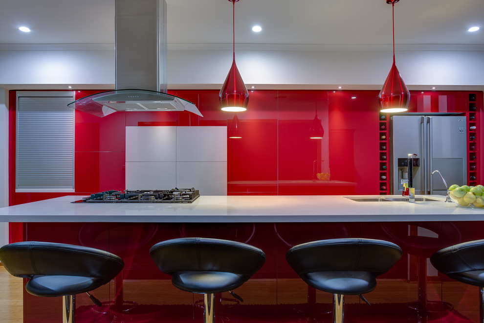 Inredning av ett modernt kök, med en dubbel diskho, öppna hyllor, röda skåp, bänkskiva i koppar, rostfria vitvaror, ljust trägolv och en köksö