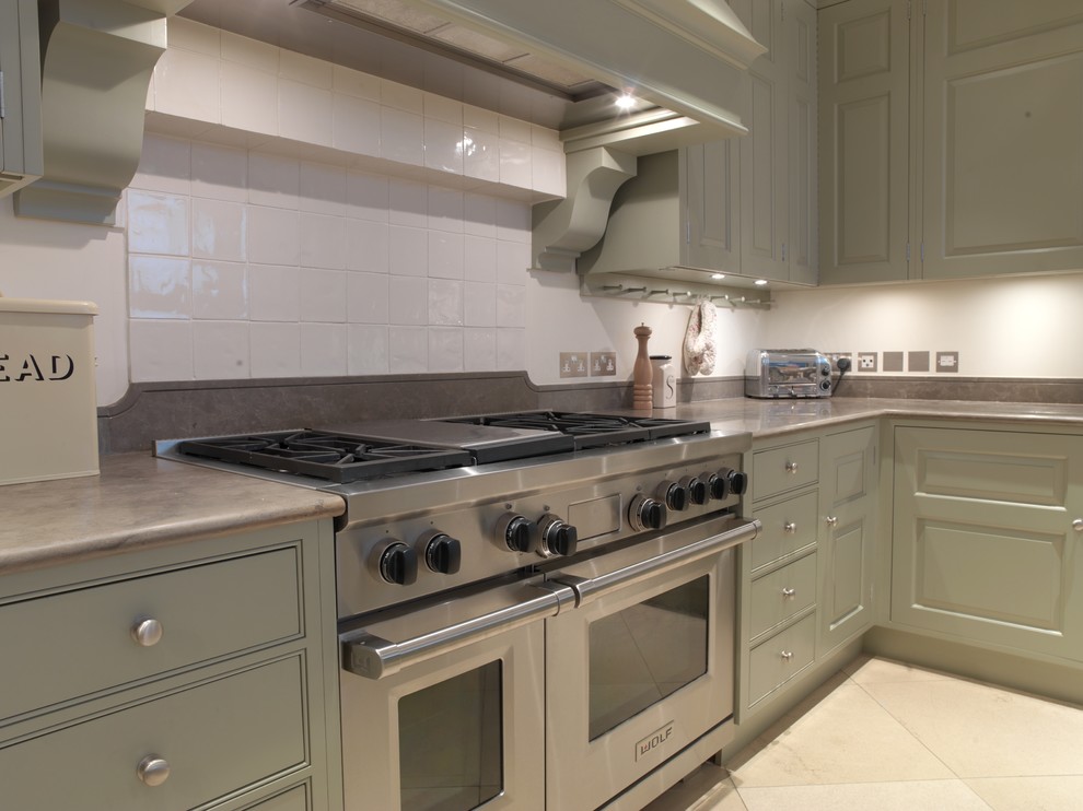 Exempel på ett stort modernt kök och matrum, med en undermonterad diskho, luckor med upphöjd panel, gröna skåp, bänkskiva i kalksten, vitt stänkskydd, rostfria vitvaror, kalkstensgolv och en köksö