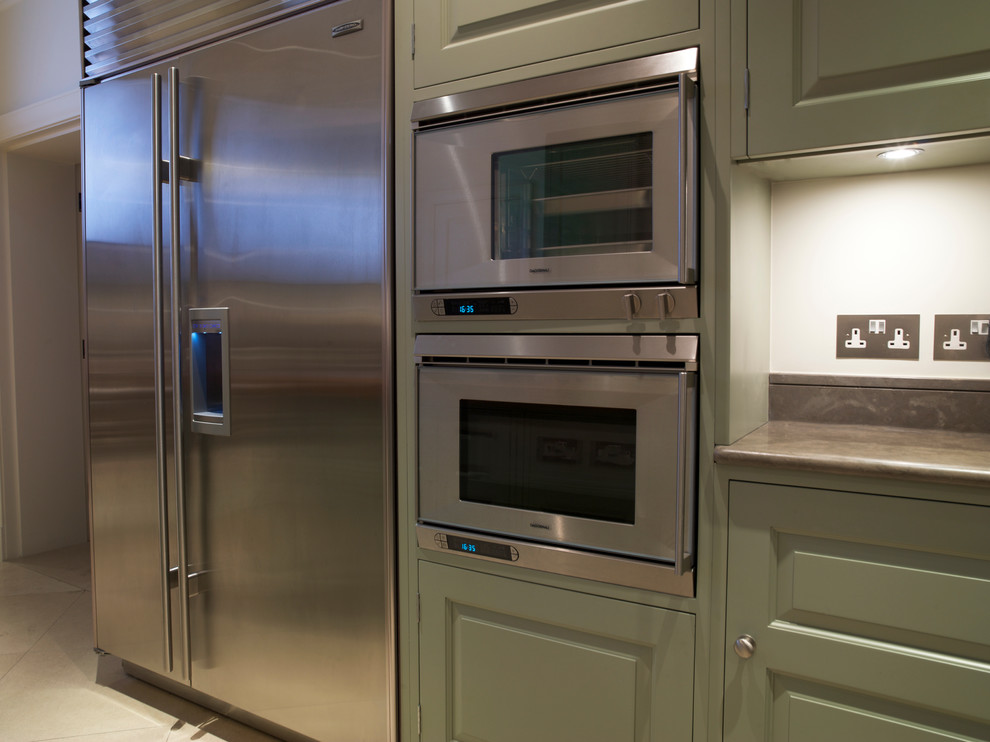 Exempel på ett stort klassiskt kök och matrum, med en undermonterad diskho, luckor med upphöjd panel, gröna skåp, bänkskiva i kalksten, vitt stänkskydd, rostfria vitvaror, kalkstensgolv och en köksö