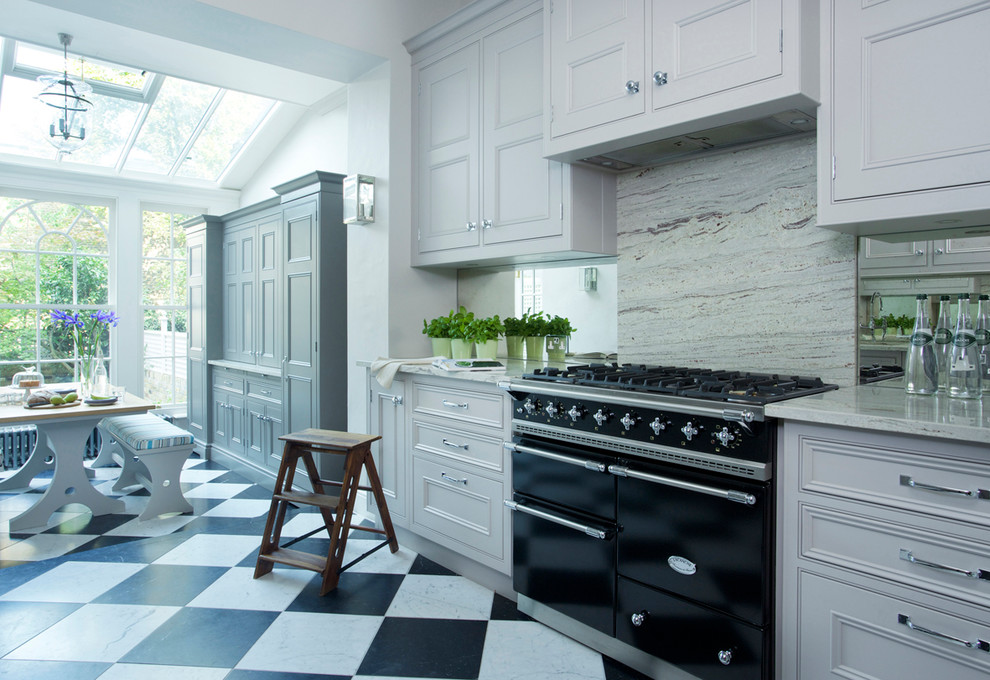 Klassisk inredning av ett mycket stort kök, med en undermonterad diskho, luckor med profilerade fronter, grå skåp, granitbänkskiva, stänkskydd med metallisk yta, glaspanel som stänkskydd, svarta vitvaror och marmorgolv