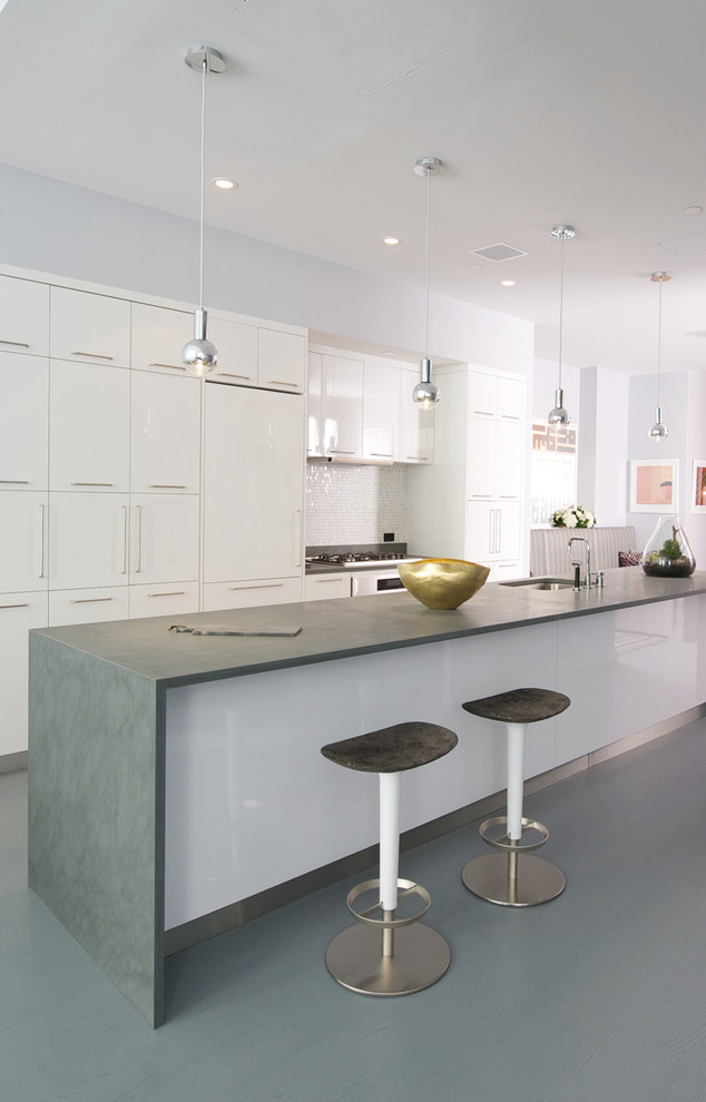 Photo of a medium sized contemporary galley kitchen/diner in New York with a submerged sink, flat-panel cabinets, white cabinets, white splashback, mosaic tiled splashback, granite worktops, an island and stainless steel appliances.