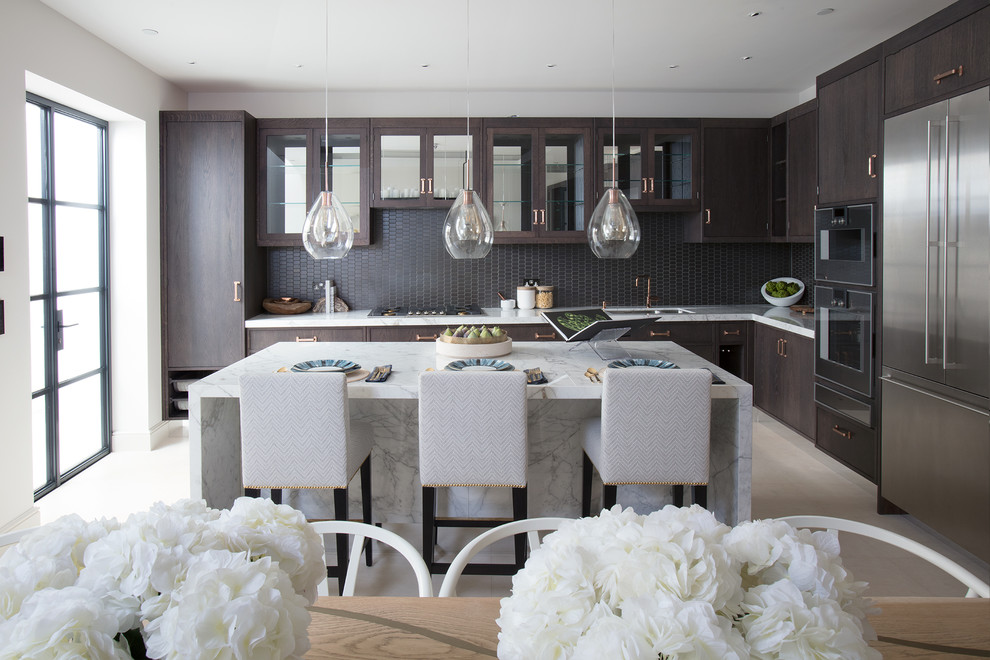 Example of a transitional l-shaped beige floor eat-in kitchen design in London with an undermount sink, flat-panel cabinets, dark wood cabinets, gray backsplash, mosaic tile backsplash, stainless steel appliances, an island and white countertops