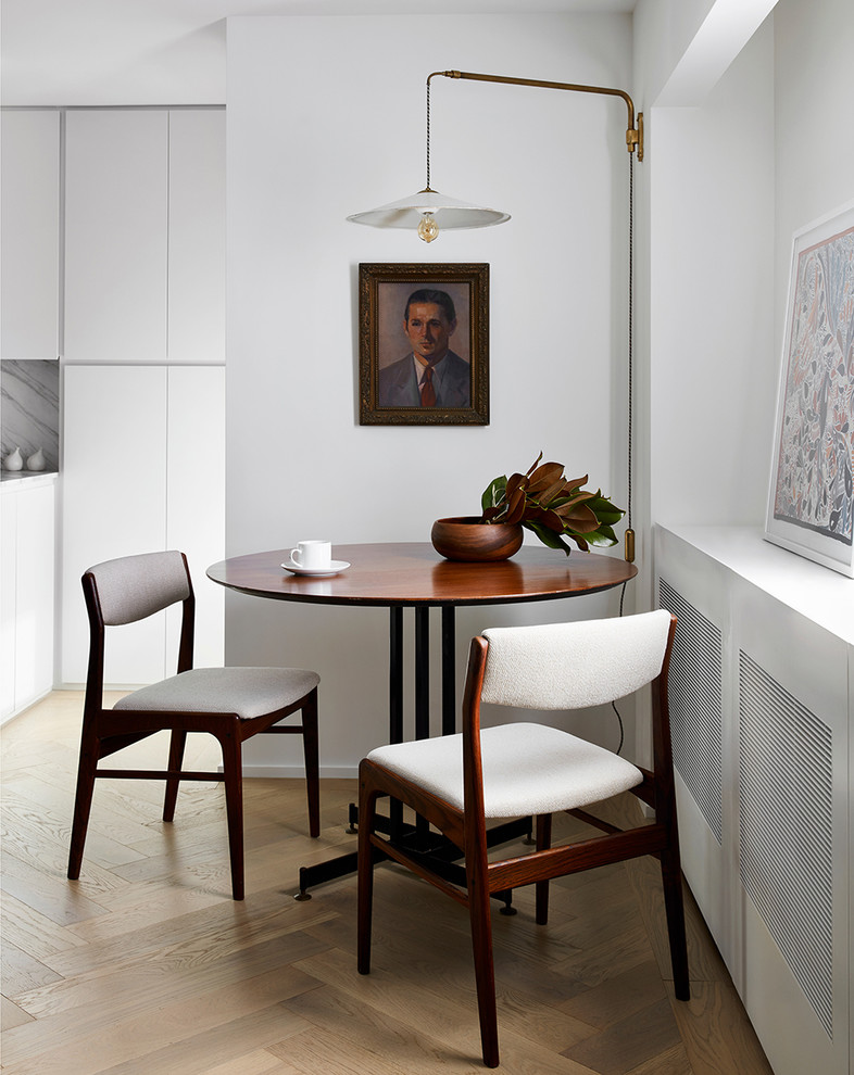 Стильный дизайн: параллельная кухня среднего размера в современном стиле с обеденным столом, плоскими фасадами, белыми фасадами, белым фартуком, фартуком из каменной плиты, светлым паркетным полом, коричневым полом и белой столешницей - последний тренд
