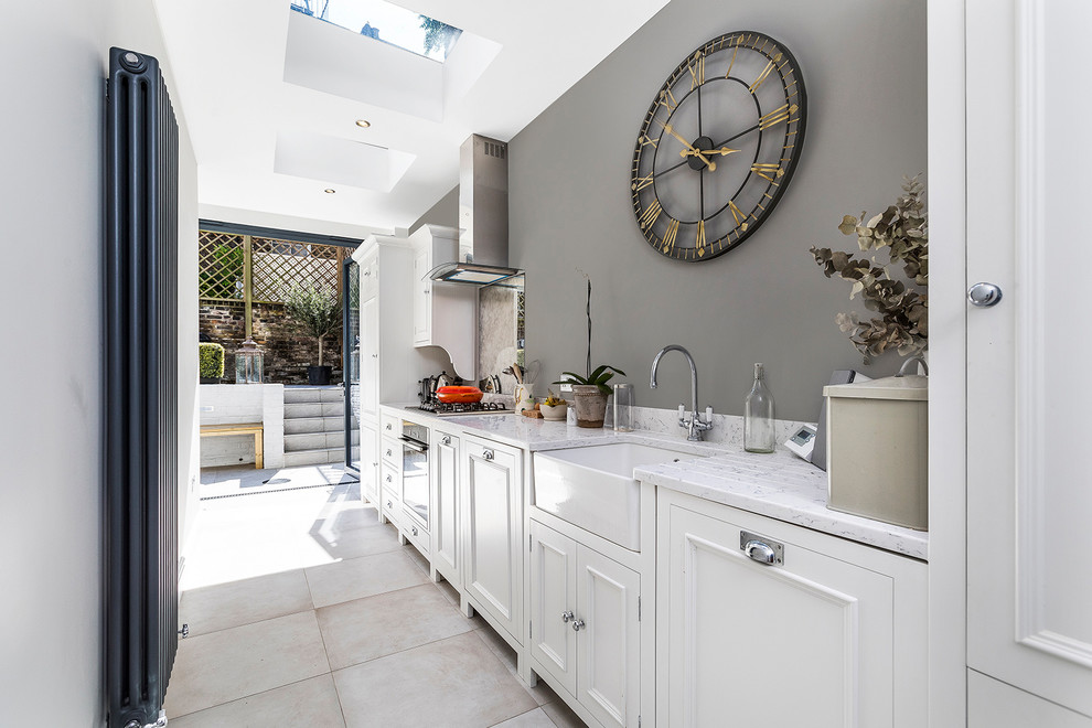 Small traditional single-wall kitchen in London with white cabinets, marble worktops, cement flooring, no island, grey floors, a belfast sink, recessed-panel cabinets and mirror splashback.