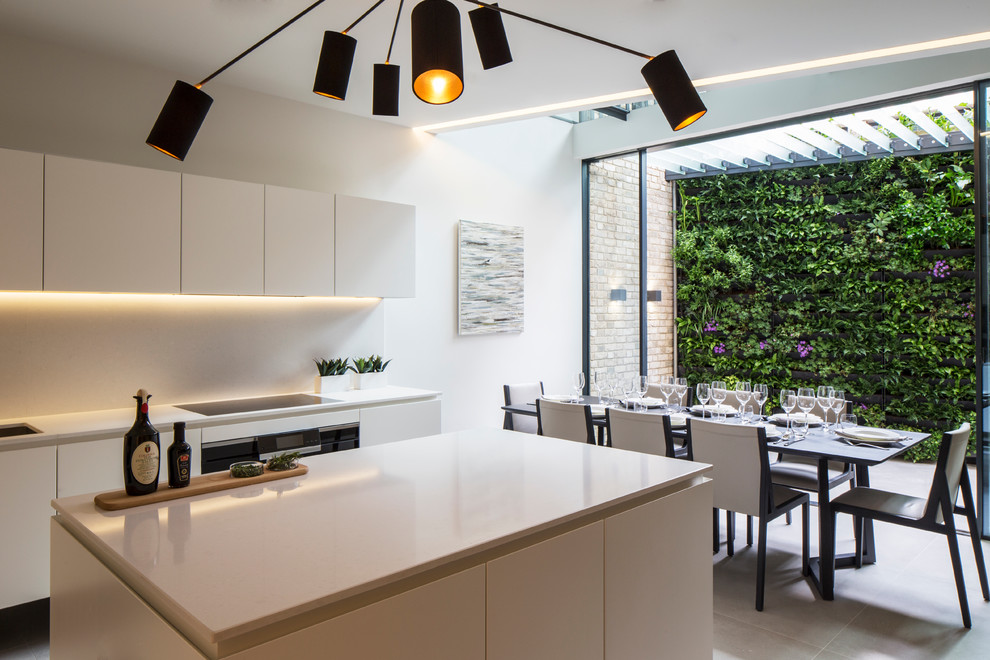 Moderne Wohnküche mit flächenbündigen Schrankfronten, Küchenrückwand in Weiß und Kücheninsel in London