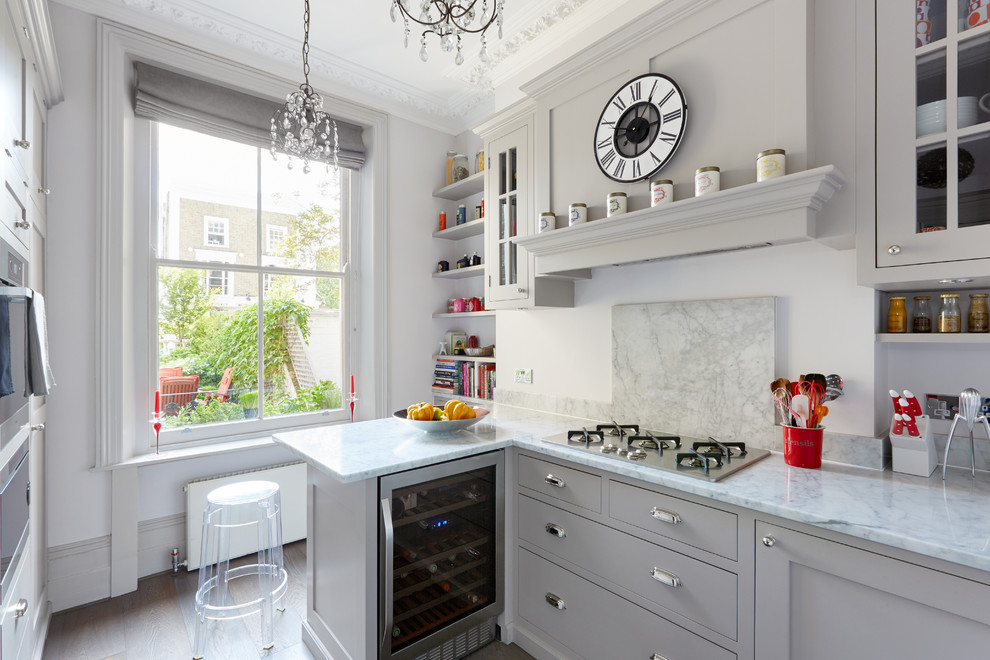 Klassische Küche in L-Form mit Schrankfronten im Shaker-Stil, grauen Schränken, Küchengeräten aus Edelstahl, braunem Holzboden und Halbinsel in London
