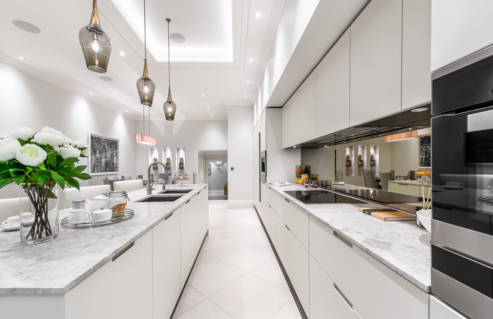 Exempel på ett stort modernt vit vitt kök med öppen planlösning, med en dubbel diskho, släta luckor, vita skåp, marmorbänkskiva, stänkskydd med metallisk yta, stänkskydd i glaskakel, integrerade vitvaror, kalkstensgolv, en köksö och gult golv