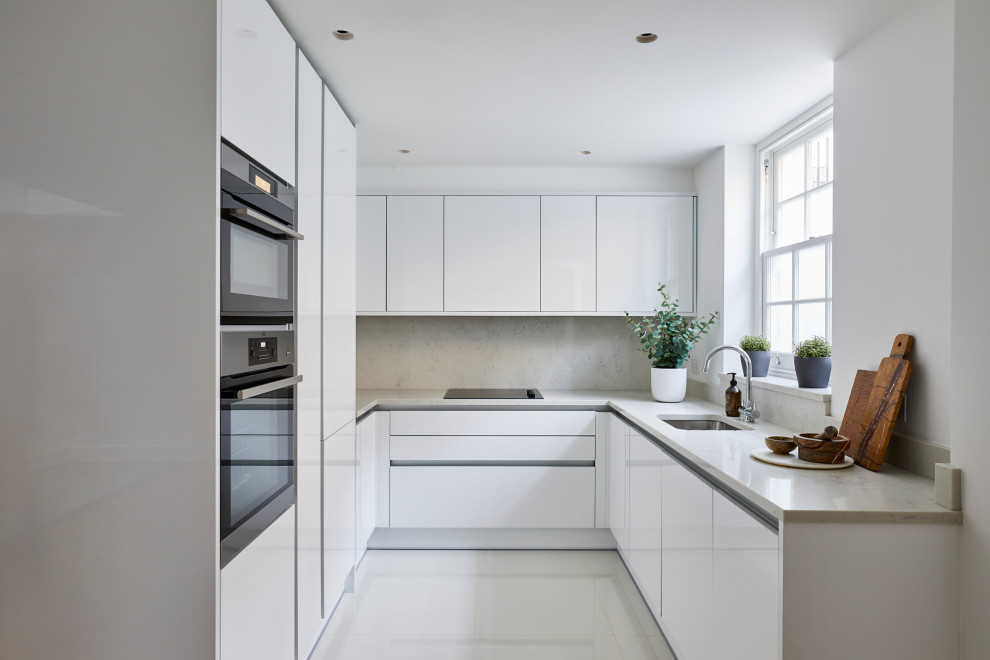 This is an example of a small contemporary u-shaped kitchen/diner in London with a submerged sink, flat-panel cabinets, white cabinets, marble worktops, grey splashback, marble splashback, integrated appliances, porcelain flooring, no island, white floors and grey worktops.