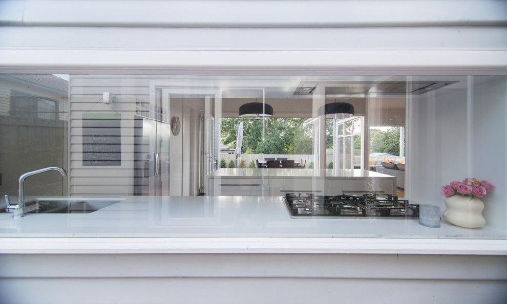 メルボルンにある広いコンテンポラリースタイルのおしゃれなアイランドキッチン (ダブルシンク、白いキャビネット、ガラス板のキッチンパネル、シルバーの調理設備、無垢フローリング) の写真