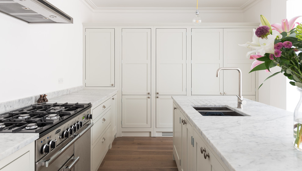 Ejemplo de cocina clásica pequeña abierta con armarios estilo shaker, puertas de armario de madera clara, encimera de mármol y suelo de madera clara