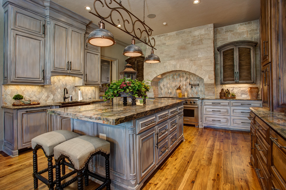 Enclosed kitchen - large rustic l-shaped medium tone wood floor and brown floor enclosed kitchen idea in Little Rock with a farmhouse sink, recessed-panel cabinets, gray cabinets, granite countertops, gray backsplash, stainless steel appliances, an island and stone tile backsplash
