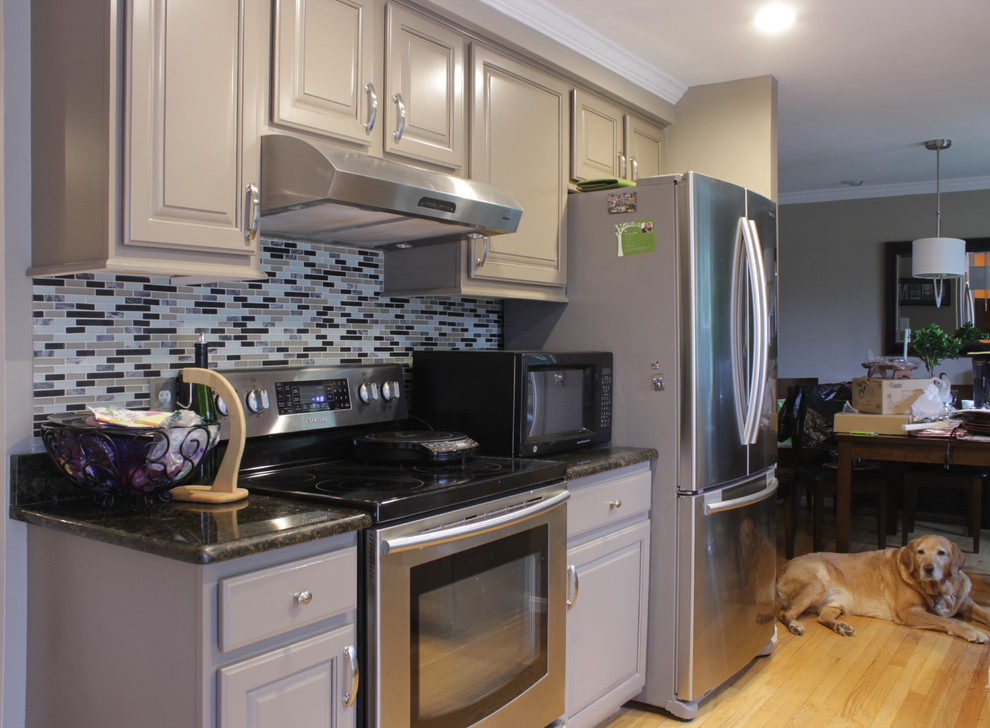 Exempel på ett mellanstort klassiskt kök, med en undermonterad diskho, luckor med upphöjd panel, grå skåp, granitbänkskiva, grått stänkskydd, stänkskydd i glaskakel, rostfria vitvaror, ljust trägolv och en halv köksö