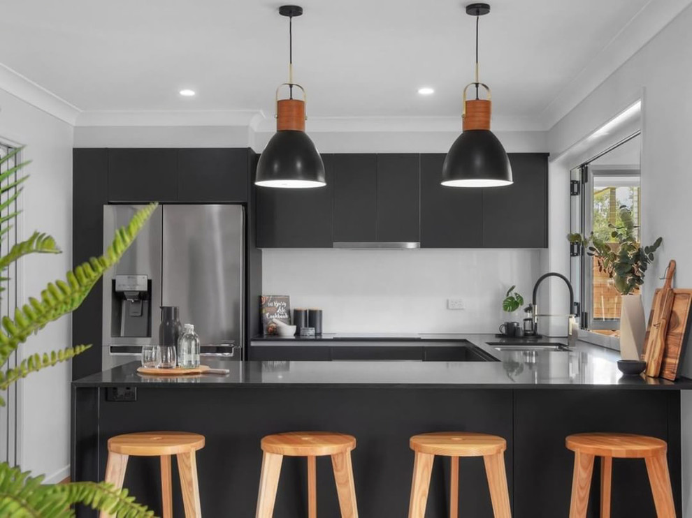 Immagine di una cucina minimal di medie dimensioni con lavello sottopiano, ante nere, paraspruzzi bianco, elettrodomestici in acciaio inossidabile, pavimento in legno massello medio, pavimento marrone e top nero