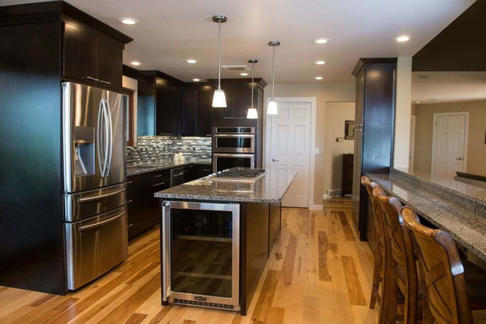 Bild på ett mellanstort vintage linjärt kök och matrum, med en köksö, granitbänkskiva, stänkskydd i mosaik, rostfria vitvaror, en enkel diskho, släta luckor, ljust trägolv, brunt golv, bruna skåp och grått stänkskydd