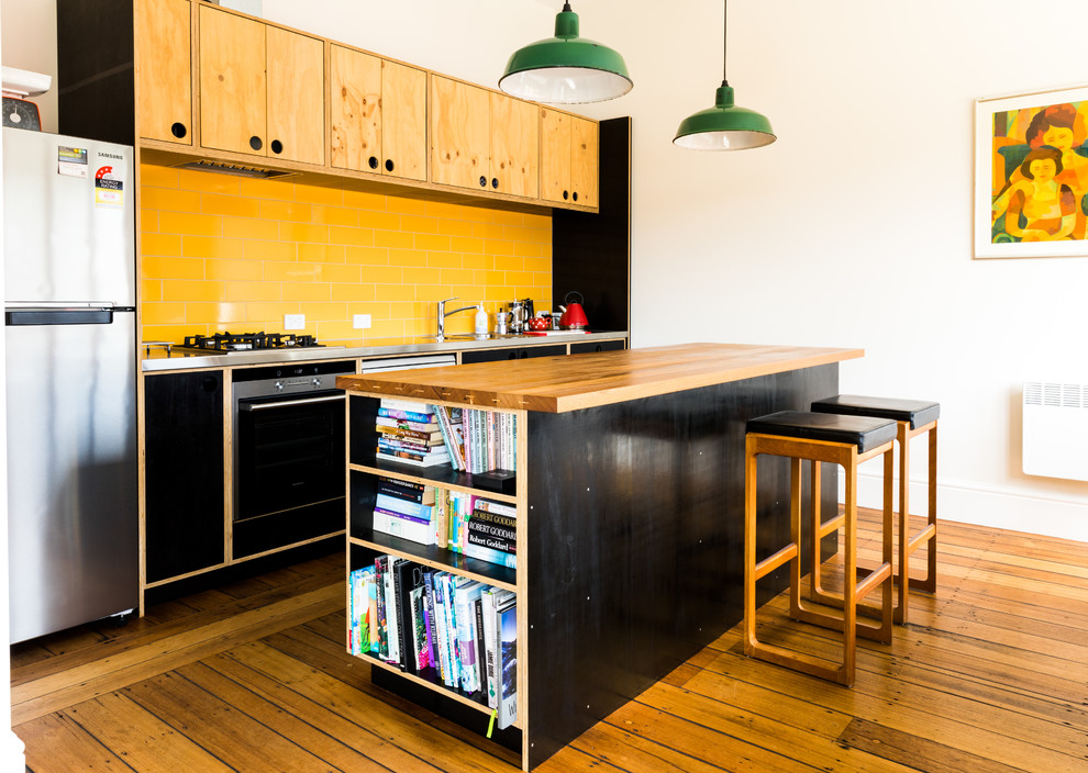 Zweizeilige Moderne Küche mit Einbauwaschbecken, flächenbündigen Schrankfronten, schwarzen Schränken, Küchenrückwand in Gelb, Rückwand aus Metrofliesen, Küchengeräten aus Edelstahl, braunem Holzboden und Kücheninsel in Hobart