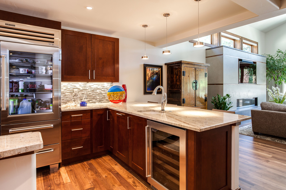 Large transitional l-shaped light wood floor open concept kitchen photo in Denver with a farmhouse sink, flat-panel cabinets, dark wood cabinets, granite countertops, multicolored backsplash, subway tile backsplash, stainless steel appliances and an island