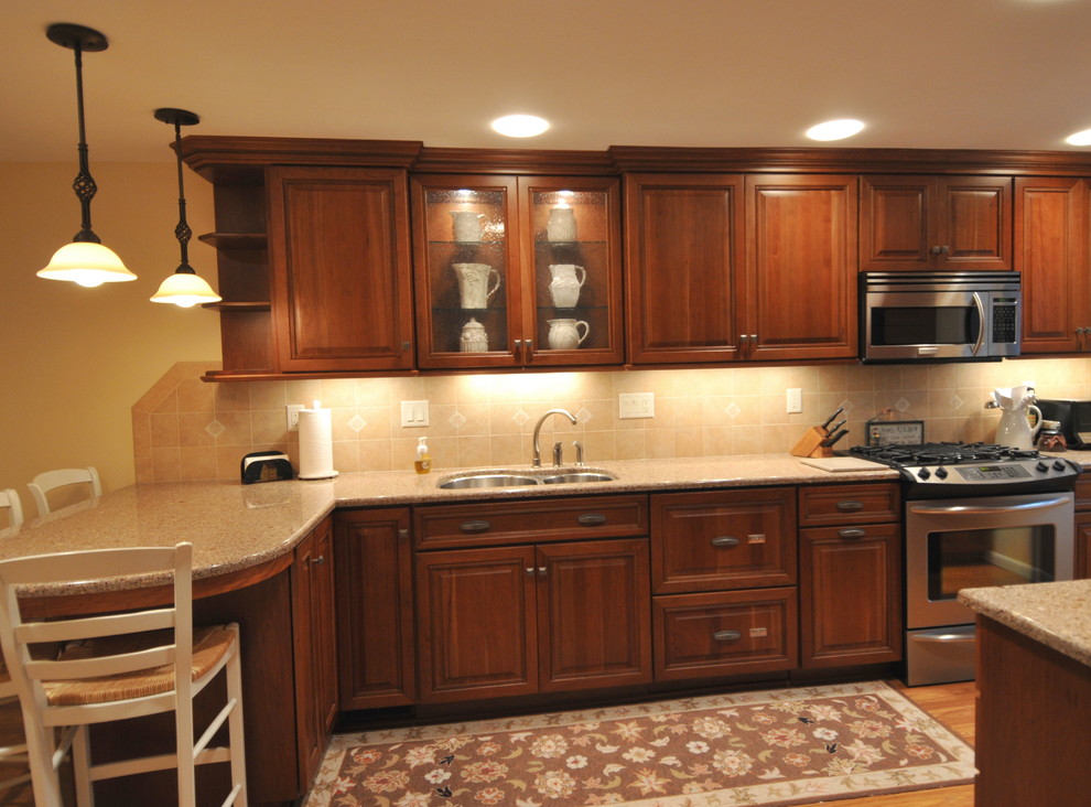 Bild på ett mellanstort vintage kök, med en undermonterad diskho, luckor med upphöjd panel, skåp i mellenmörkt trä, bänkskiva i kvarts, rostfria vitvaror, mellanmörkt trägolv, en halv köksö, beige stänkskydd och stänkskydd i keramik