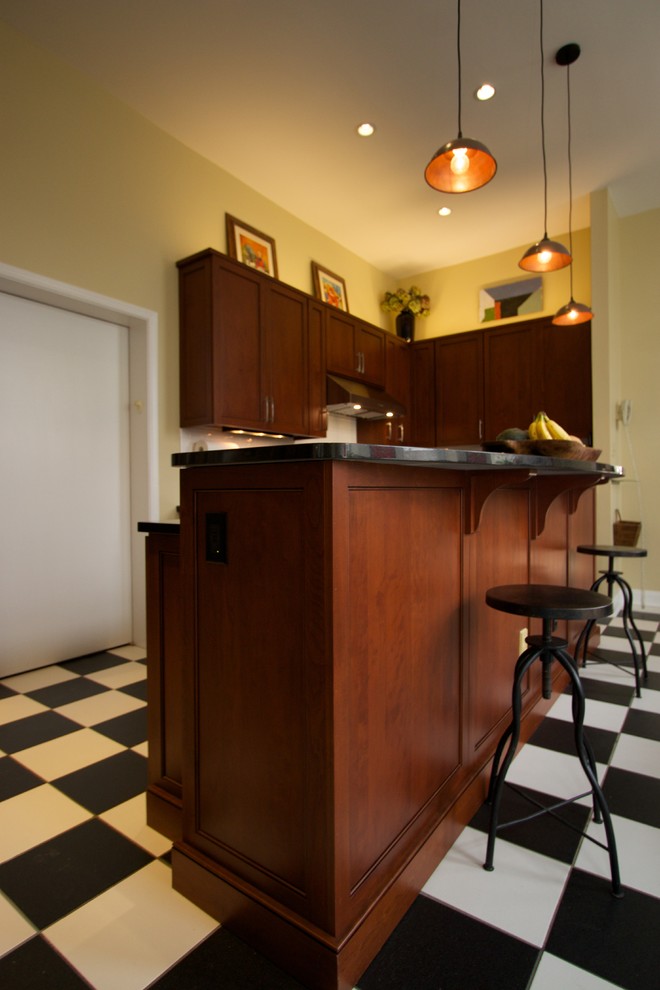 Klassisk inredning av ett kök, med luckor med infälld panel, skåp i mellenmörkt trä, granitbänkskiva, vitt stänkskydd, rostfria vitvaror och en köksö
